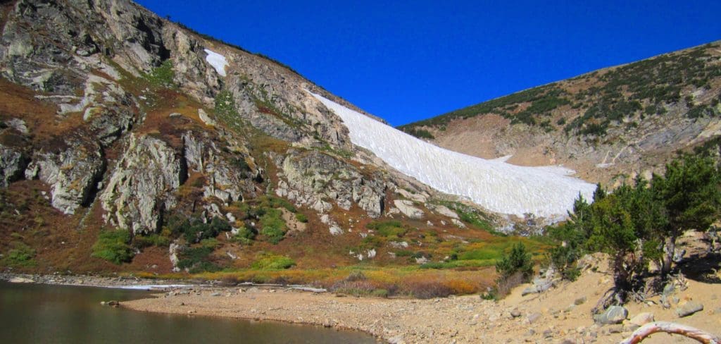 Mountains with snow in between and lake in front