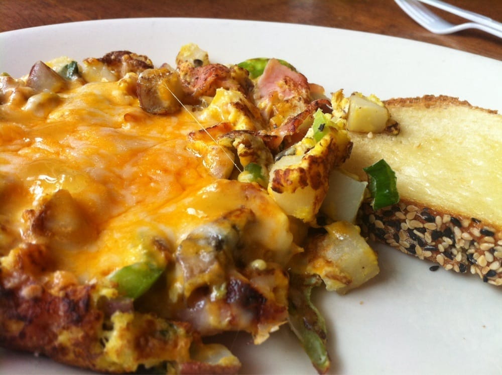 Egg scramble with ham, green peppers, potatoes, covered in cheese with a side of buttery toast